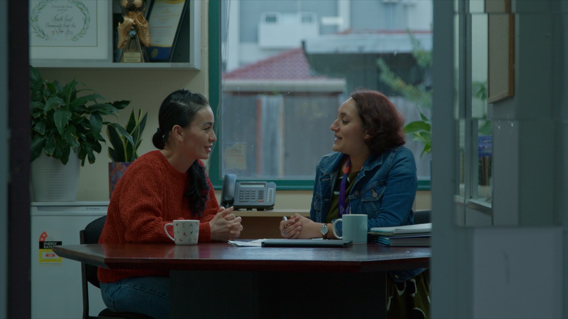 Two women are seated in an office speaking